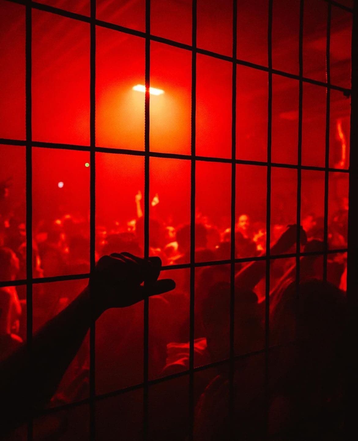 Menge hinter Gitter in rotem Licht